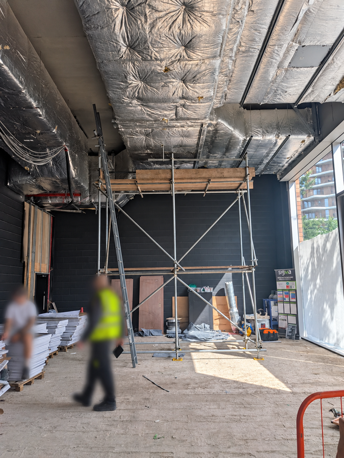 Internal scaffold tower positioned beneath overhead ductwork at M&S in Bankside, London