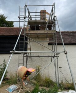 Three-lift chimney scaffold tower with two rakers against a building with black weatherboarding in Guildford