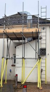 Yellow ladder gate and clamped scaffold boards on the top lift beside the chimney exhaust at Park House Hotel, Midhurst