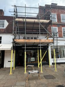 Two-lift scaffold on the pavement in front of the Cat & Rabbit Rescue Centre on North Street, Chichester, with yellow foam on the standards
