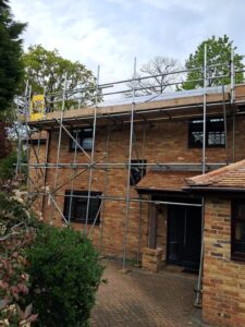 Three-lift scaffold on the front of a two-storey brick house in Finchampstead, Wokingham, built partly over a single-storey roof for access to solar panels