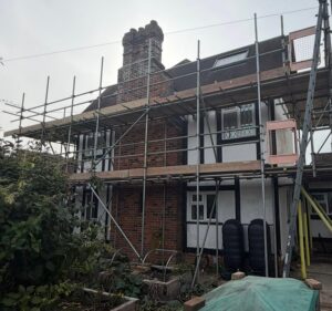 Scaffold with ladder gates and boarded lifts along a Tudor-style house in Worthing